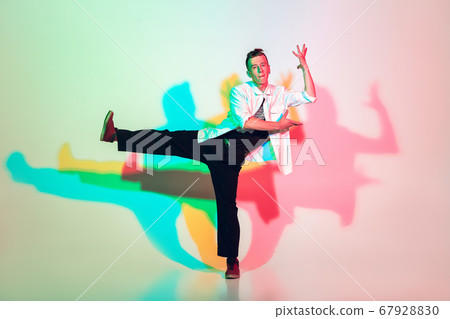 Young beautiful man dancing hip-hop, street style isolated on studio background in neon light Young beautiful man dancing hip-hop, street style isolated on studio background in neon light 67928830