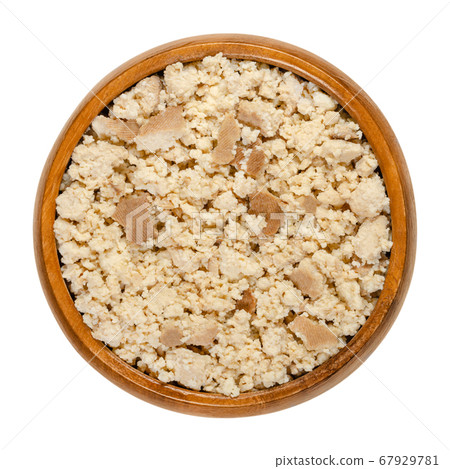Smoked tofu, bean curd, crumbled by hand, in a wooden bowl. Coagulated soy milk, a component of Asian cuisine and meat substitute. Close-up from above, on white background, isolated macro food photo. Smoked tofu, bean curd, crumbled by hand, in a wooden bowl. Coagulated soy milk, a component of Asian cuisine and meat substitute. Close-up from above, on white background, isolated macro food photo. 67929781