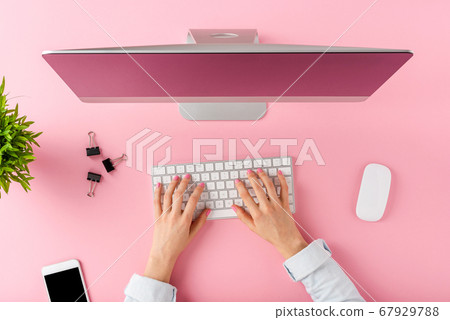 Female hands using modern computer with business accessories on pink background. Office desktop. Top view 67929788