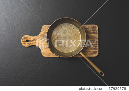 Frying pan on wooden board. Top view 67929876