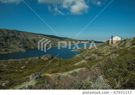Rocky landscape with lake and house on highlands Rocky landscape with lake and house on highlands 67931157