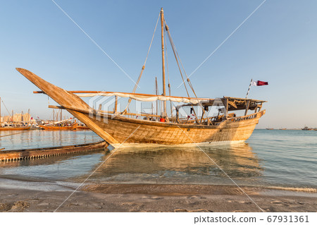Traditional wooden boat (dhow) in Arabic gulf with Qatari flag Traditional wooden boat (dhow) in Arabic gulf with Qatari flag 67931361