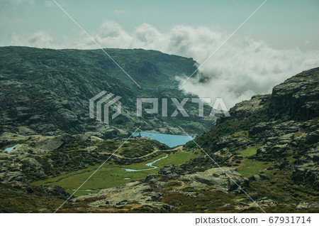 Hilly landscape with clouds coming from the ravine Hilly landscape with clouds coming from the ravine 67931714