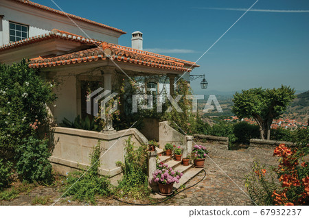 Old house with stairs leading to porch full of flowers at Monsanto 67932237