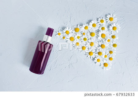 Mock-up of unbranded brown plastic spray bottle and chamomiles on a pastel gray background. Natural organic spa cosmetics, Spray concept. Body mist, brume corps. Flower flatlay. 67932633