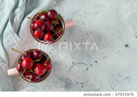 Two pink mugs with fresh ripe cherries. Two pink mugs with fresh ripe cherries. 67933976