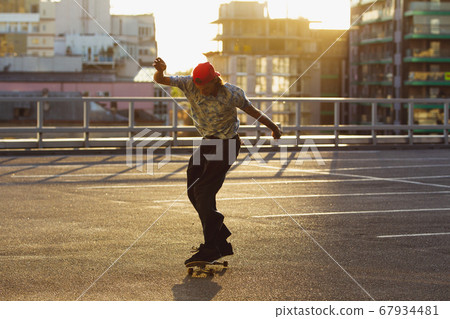 Skateboarder doing a trick at the city's street in summer's sunshine Skateboarder doing a trick at the city's street in summer's sunshine 67934481