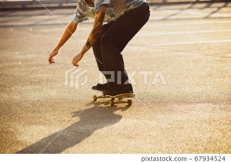 Skateboarder doing a trick at the city's street in summer's sunshine Skateboarder doing a trick at the city's street in summer's sunshine 67934524
