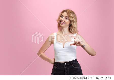 Caucasian young woman's portrait isolated on pink studio background. Beautiful female model. Concept of human emotions, facial expression, sales, ad, youth culture. Caucasian young woman's portrait isolated on pink studio background. Beautiful female model. Concept of human emotions, facial expression, sales, ad, youth culture. 67934573