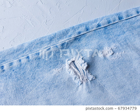 Blue holey jeans on a concrete gray background. Denim. Hole on the fabric Blue holey jeans on a concrete gray background. Denim. Hole on the fabric 67934779