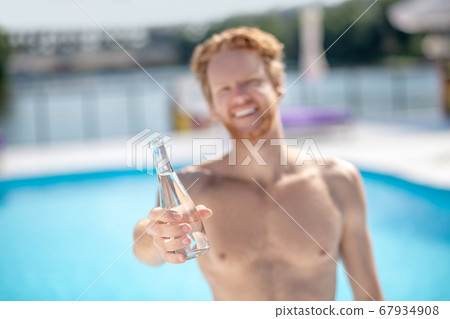 Bottle of drinking water in mans outstretched hand. Bottle of drinking water in mans outstretched hand. 67934908