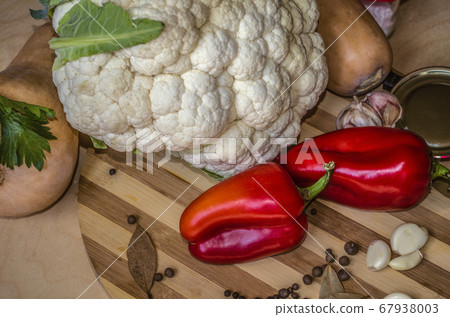 Round wooden chopping board with red pepper, garlic, cauliflower, pumpkin with spices and celery leaves Round wooden chopping board with red pepper, garlic, cauliflower, pumpkin with spices and celery leaves 67938003