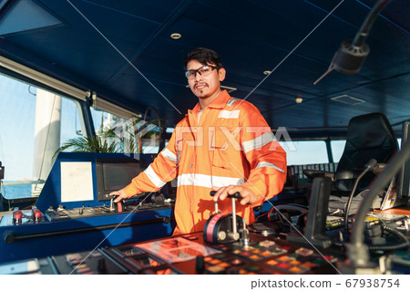 Filipino deck Officer on bridge of vessel or ship. He is speaking on GMDSS VHF radio Filipino deck Officer on bridge of vessel or ship. He is speaking on GMDSS VHF radio 67938754