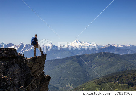 Man on the Edge of a Cliff looking at Canadian Landscape 67938763