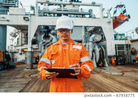 Filipino deck Officer on deck of offshore vessel or ship fills checklist. Paperwork at sea Filipino deck Officer on deck of offshore vessel or ship fills checklist. Paperwork at sea 67938775