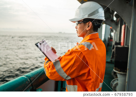 Filipino deck Officer on deck of offshore vessel or ship fills checklist. Paperwork at sea 67938793