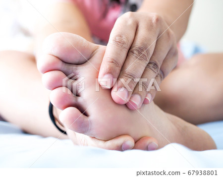 Asian woman sitting on bed Have foot pain Use hand 67938801