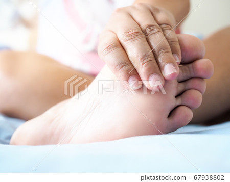 Asian woman sitting on bed Have foot pain Use hand 67938802