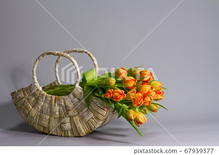 Straw basket with bouquet of fresh orange tulips 67939377