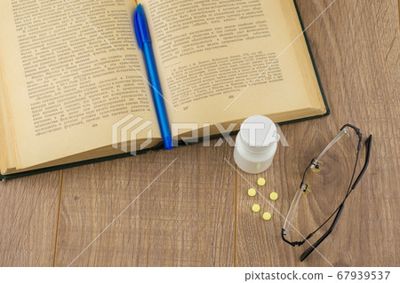 drowsiness and malaise at work: a box of caffeine pills, glasses, open book, blue pen - a view from above, close 67939537