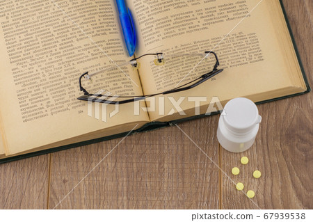 drowsiness and malaise at work: a box of caffeine pills, glasses, open book, blue pen - top view 67939538