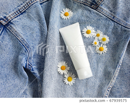 Mock-up of unbranded white bottle tube and chamomile flowers on a blue jeans background. Top view. Natural organic spa cosmetics concept. Mock-up of unbranded white bottle tube and chamomile flowers on a blue jeans background. Top view. Natural organic spa cosmetics concept. 67939575