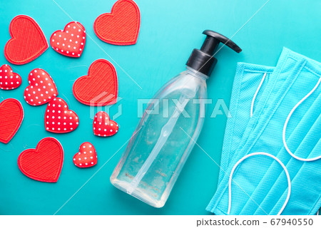Surgical masks with heart shape and hand sanitizer on green background  67940550