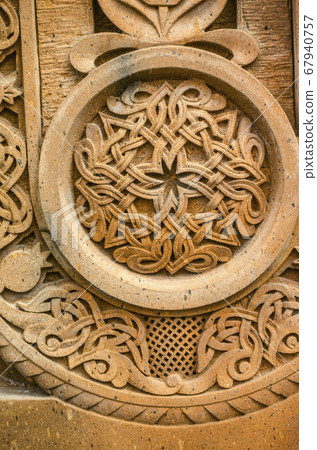 Round ornament with intertwining stripes forming a pattern on a red volcanic stone 67940757