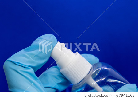 Spray disinfect liquid, hand in blue glove on blue Spray disinfect liquid, hand in blue glove on blue 67941163