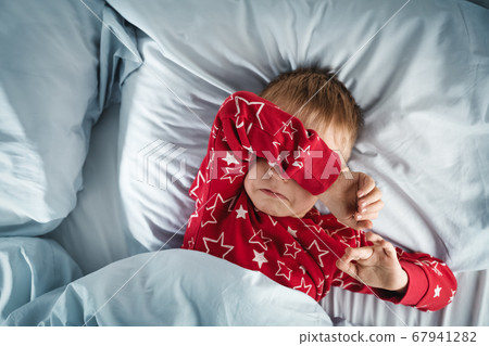 Sleepy boy lying in bed with blue beddings Sleepy boy lying in bed with blue beddings 67941282