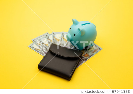 Blue piggy bank with a wallet with hundred-dollar bills on a yellow background. Family budget, savings Blue piggy bank with a wallet with hundred-dollar bills on a yellow background. Family budget, savings 67941588