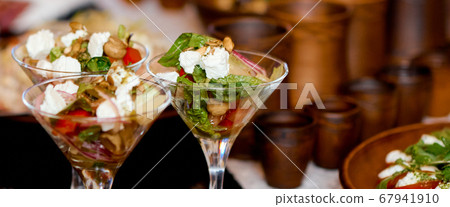 Three servings of salad in martini glasses on the table. Clay utensils in the background. Three servings of salad in martini glasses on the table. Clay utensils in the background. 67941910