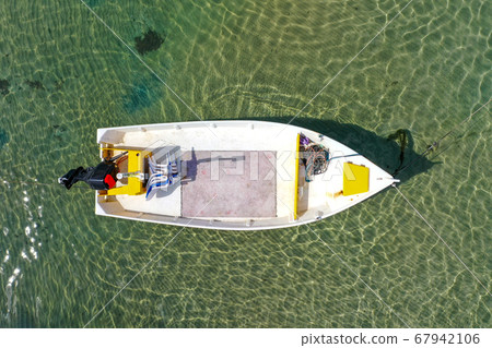 Small Fishing Boat anchored in a shallow lagoon. 67942106