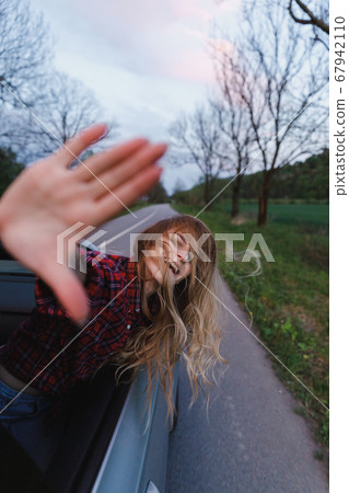 Beautiful blond girl climbed out of car window, looks and catches wind Beautiful blond girl climbed out of car window, looks and catches wind 67942110