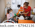 Little girl and dentist brushing teeth of toy 67942136