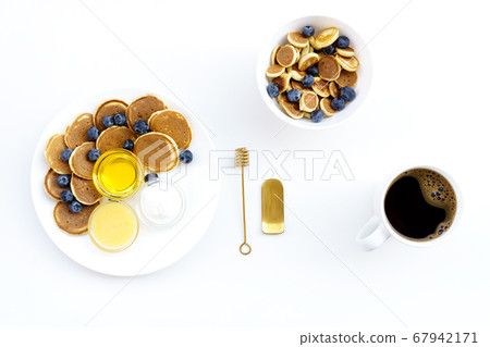 Mini Pancake cereal and middle size pancakes with honey, yogurt or milk and blueberry and black coffee. 67942171