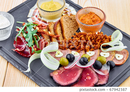 A wooden table topped with plates of meat plate 67942387