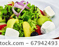 Food on a plate next to a Greek salad 67942493