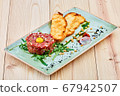 A beef tartare sitting on top of a wooden cutting board 67942507