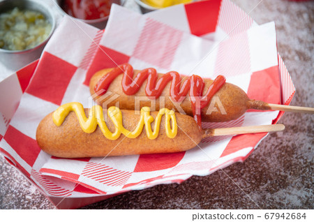 corn dog with ketchup and yellow mustard 67942684