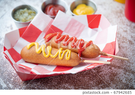 corn dog with ketchup and yellow mustard 67942685