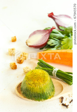 Frozen broth with herbs and seasonings on a wooden spoon, vertical frame with space 67943570
