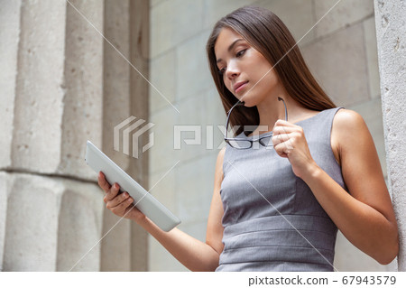 Tablet business woman worker serious working at office or courthouse reading news email. Asian Businesswoman lawyer using pc computer with reading glasses. Multiracial Caucasian Chinese professional 67943579