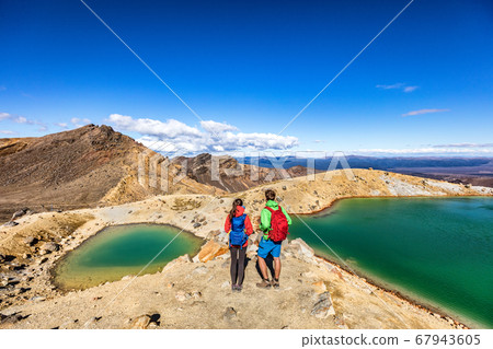 New Zealand popular tourist hiking hike in Tongariro Alpine Crossing National Park. Tramping trampers couple hikers walking on famous destination in NZ 67943605