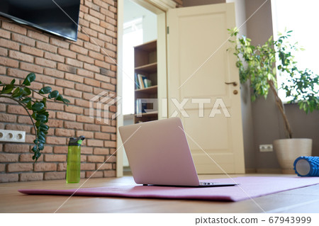 Online workout at home concept. Laptop computer on yoga mat on floor. 67943999