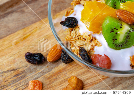 Bowl of granola with youghurt and sliced fruits Bowl of granola with youghurt and sliced fruits 67944509