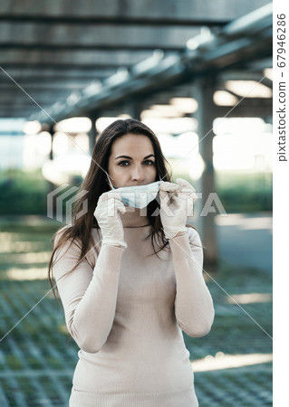 A girl with beautiful eyes wears a protective mask on her face in rubber gloves 67946286