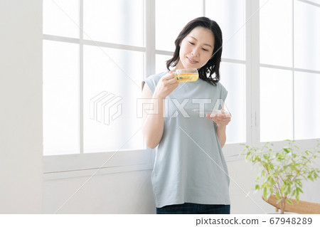 Middle women who enjoy herbal tea indoors [Prevention of cold] 67948289