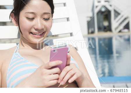 一個女人在泳裝看著手機郵件 67948515