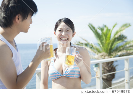 Men and women barbecuing on the beach Men and women barbecuing on the beach 67949978